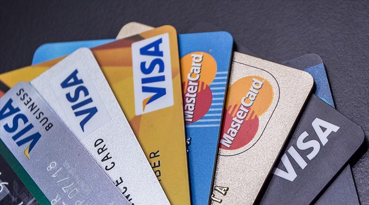 Fanned Visa and Mastercard credit cards on a dark surface, showing blue, gold, silver, and black card designs.