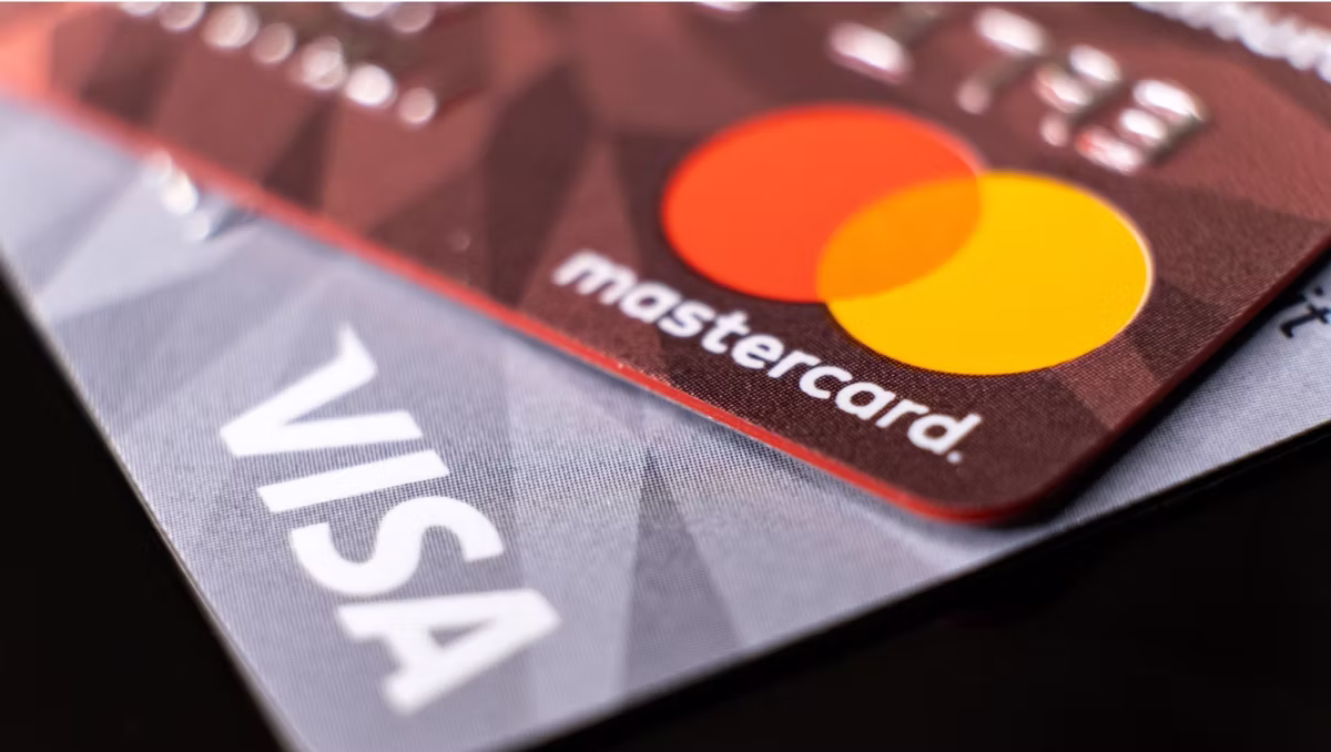Close-up of overlapping credit cards: red Mastercard with orange and red circles, white text; gray Visa with white text.